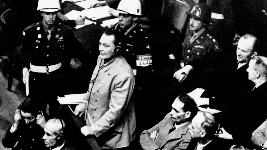 Reichsmarshal Hermann Goering stands in the prisoner's dock at the Nuremberg War Crimes Trial in Germany in Nov. 21, 1945. Goering is wearing headphones of the court translating system. [ AP ]