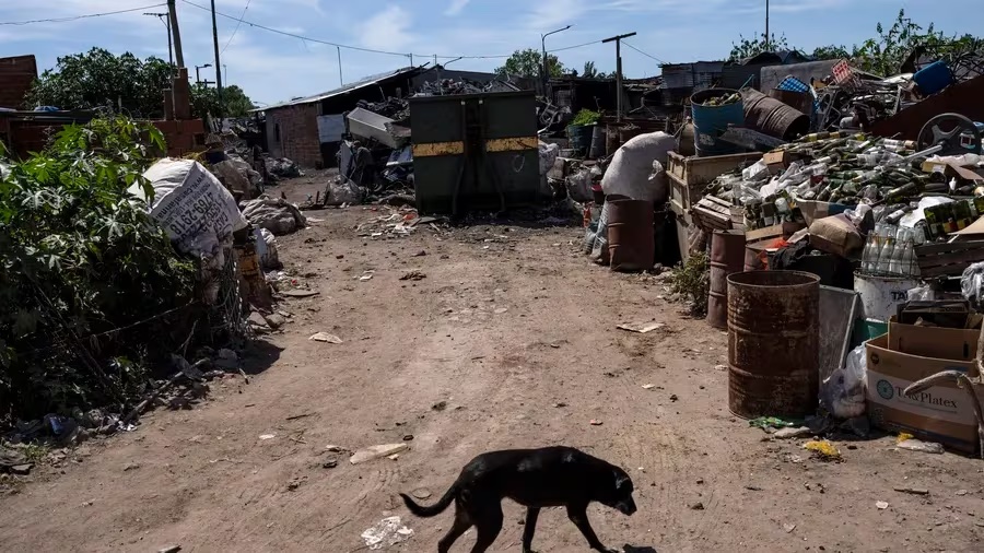 A dog walks in a yard where items collected for recycling accumulate in La Esperanza neighborhood of Buenos Aires, Argentina, on Feb. 22. An Oxfam report says that "Since 2020, the richest five men in the world have doubled their fortunes. During the same period, almost five billion people globally have become poorer. Hardship and hunger are a daily reality for many people worldwide. At current rates, it will take 230 years to end poverty, but we could have our first trillionaire in 10 years.” (AP Photo/Rodrigo Abd) [ RODRIGO ABD | AP ]